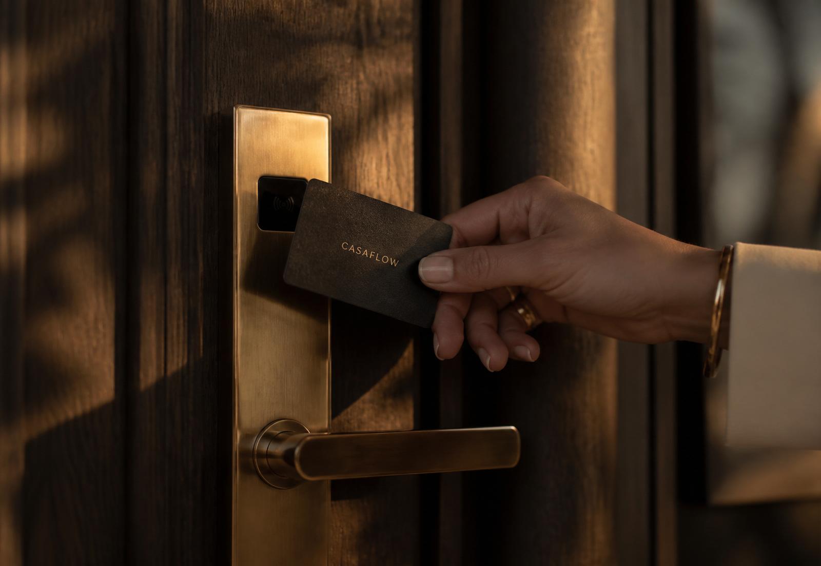Hand holding a CasaFlow NFC card against a smart door lock